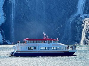 The Chugach Express catamaran boat shown in front of a waterfall and glacier