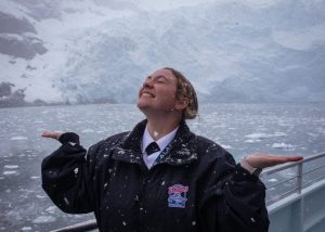 Senior Deckhand Noel in front of a tidewater glacier enjoying the snowfall in early May