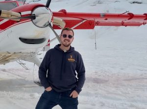 Shore Operations Manger Matt Schonoff in front of a prop plane during a glacier landing